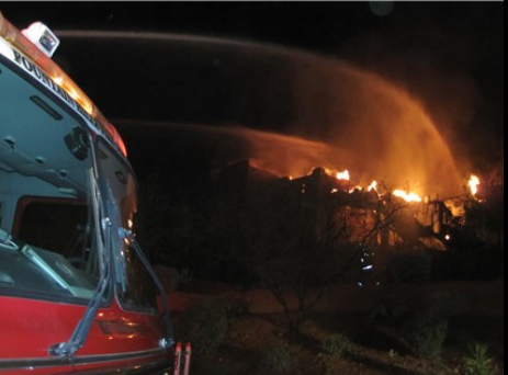 Water is sprayed from truck over a buring area at